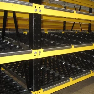 Close-up view of industrial warehouse shelving with black frames and yellow beams, featuring slanted roller tracks for moving goods—an efficient choice for modern warehouse solutions.
