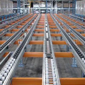 Rows of industrial roller conveyors in a warehouse, part of innovative warehouse solutions for moving goods and materials along metal frames with orange supports.