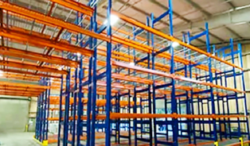 Large, empty Double-Deep Rack warehouse shelving units with orange horizontal beams and blue supports under a high ceiling, ready for storage use.