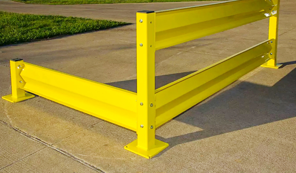 A yellow metal Industrial Warehouse Safety Guarding rail is installed on a concrete surface, forming a sturdy corner barrier near a grassy area.