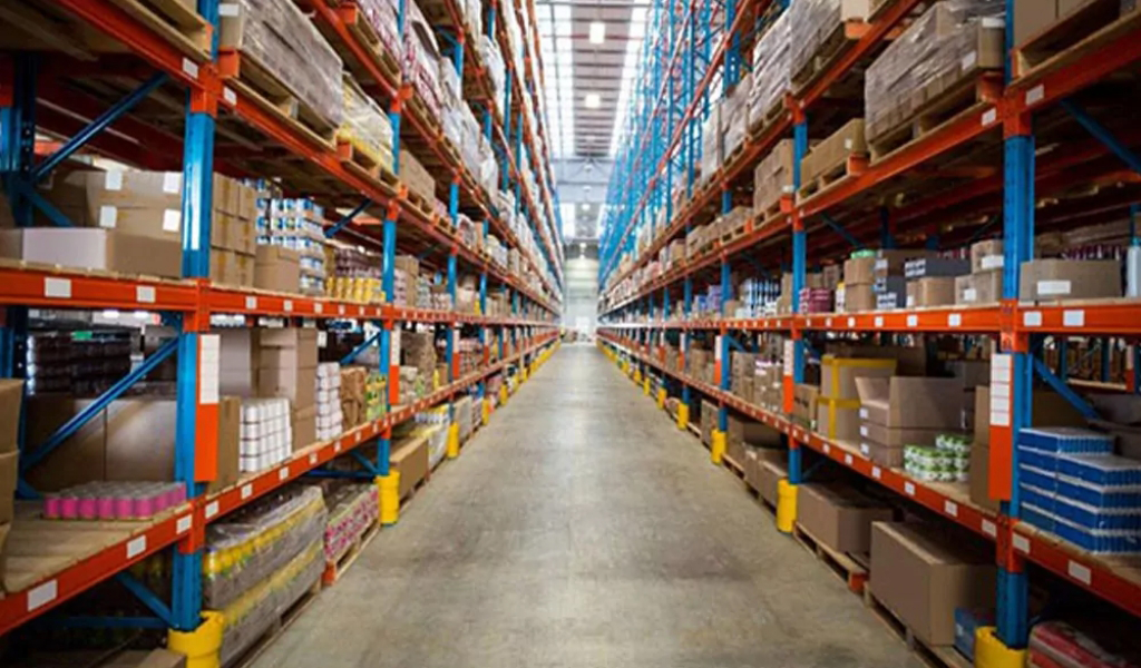 Rows of tall warehouse shelves filled with stacked boxes and packages, with a wide, empty aisle running down the center—ideal for showcasing the diverse industries we serve.