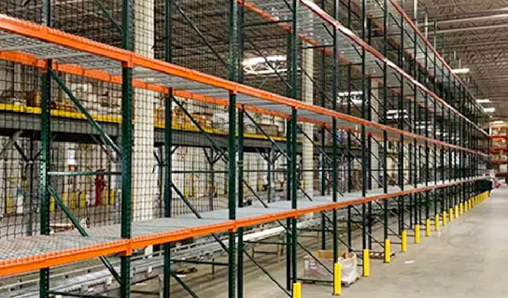 Rows of empty selective rack shelving units with metal frames and orange beams are shown inside a large, well-lit industrial warehouse.