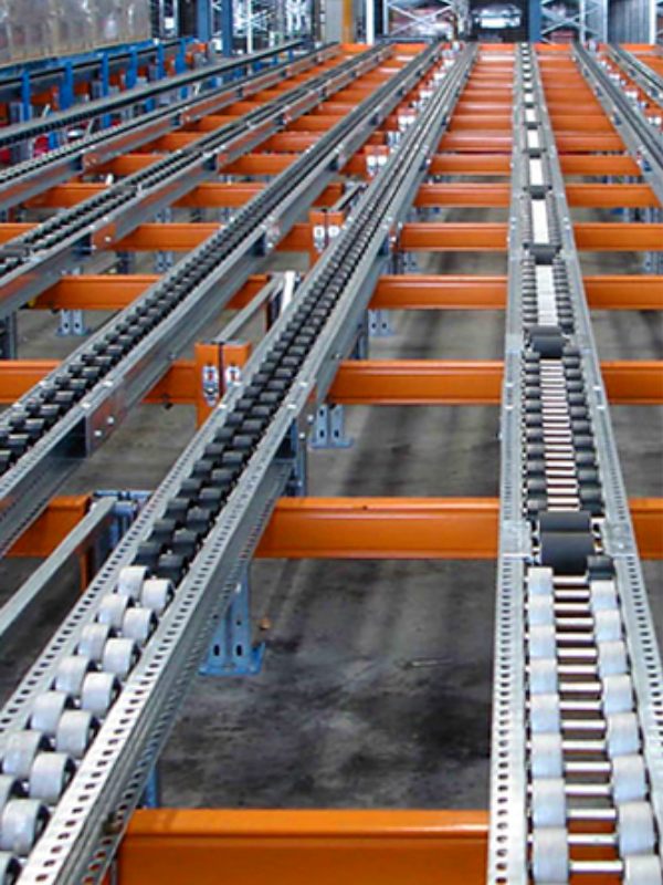 Close-up view of an industrial roller conveyor system featuring carton flow lanes, with metal rollers and orange support beams in a warehouse setting.