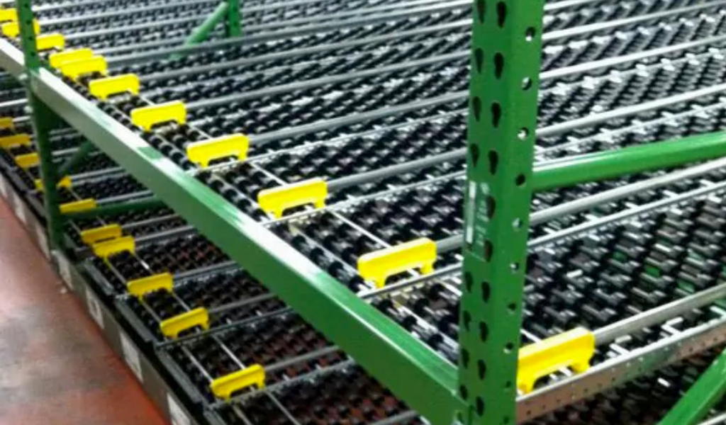 Green metal industrial carton flow roller rack with multiple rows of black rollers and yellow lane dividers, used for material handling or storage in a warehouse setting.