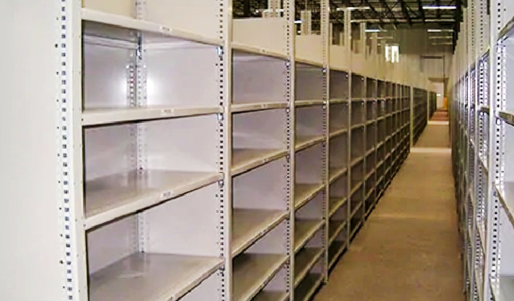Rows of empty industrial shelving units line the warehouse, creating an organized storage facility ready to be stocked, with no items currently placed on the shelves.